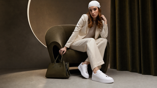 Model in ivory tailoring wearing white T-Switch luxury travel sneakers in a dramatic editorial setting